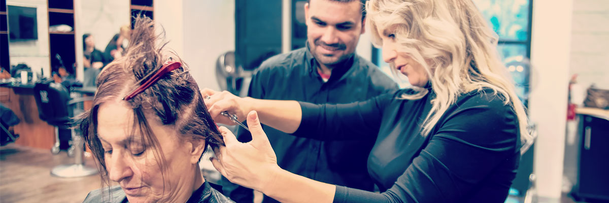 Teacher and student cut a clients hair